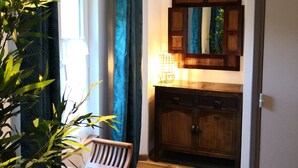 Un couloir avec un banc en bois, une porte, un meuble et un miroir accroché au mur.