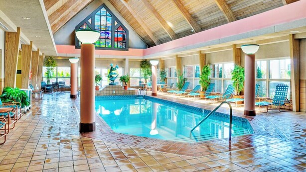An indoor swimming pool with a high ceiling, wooden beams, and a stained glass window.