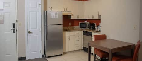 Cocina compacta con refrigerador, microondas y una mesa de comedor con sillas.