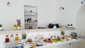 Una mesa de buffet bien organizada con diversas opciones de comida y bebida, que incluyen frutas, pastelería y salsas.