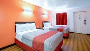 Habitación de hotel con dos camas, una cortina roja y una puerta blanca.