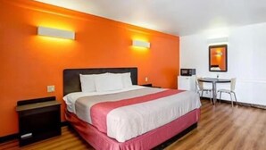 Una habitación de hotel con una cama, mesitas de noche, un escritorio y una silla.