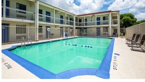 Un hotel con piscina, varios balcones y cielo despejado.