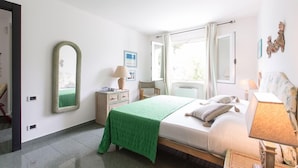 A bedroom with a bed, a green bedspread, a mirror, a dresser, and a window with curtains. - B&B Amoredimare (Polignano a Mare)