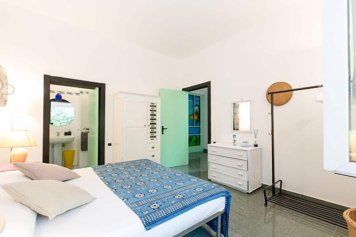 Ein Schlafzimmer mit Bett, Nachttisch, Schminktisch und Spiegel.