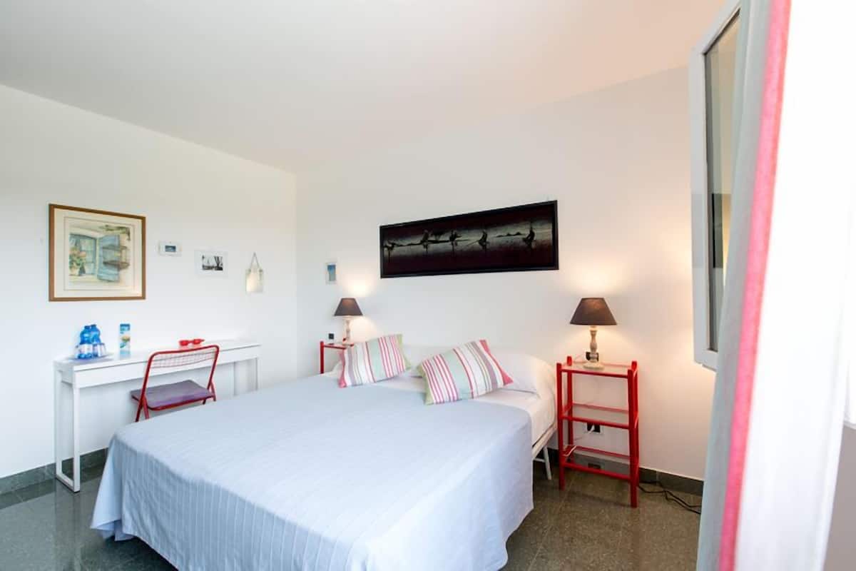 Ein ordentlich eingerichtetes Schlafzimmer mit Bett, Nachttischen, Schreibtisch und Stuhl.
