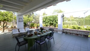 An outdoor patio with a round table set for dining, surrounded by chairs, and a pergola overhead. - B&B Amoredimare (Polignano a Mare)