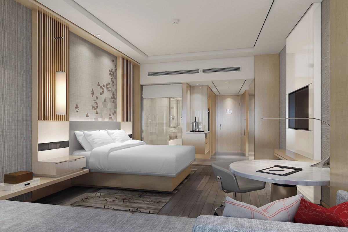 A modern hotel room with a large bed, a desk, and a TV.