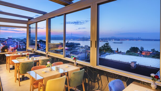 A restaurant with large windows overlooking a cityscape and a body of water. - Eastanbul Suites (Istanbul)
