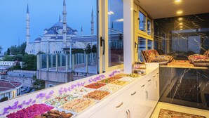 A hotel room with a large window overlooking a historic building with multiple domes and minarets. - Eastanbul Suites (Istanbul)