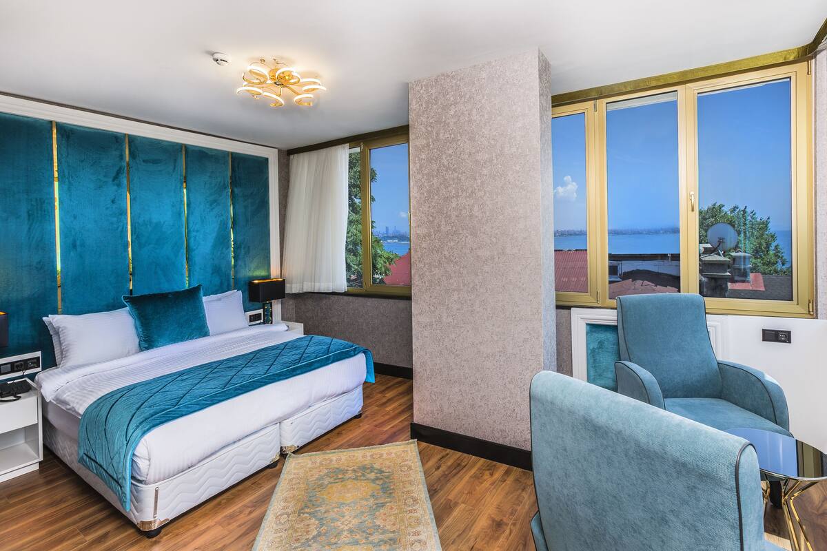 A bedroom with a large bed, a view of the sea, and a chair.
