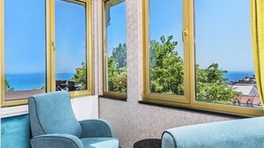 A room with a large bay window overlooking a scenic view of the sea and greenery. - Eastanbul Suites (Istanbul)
