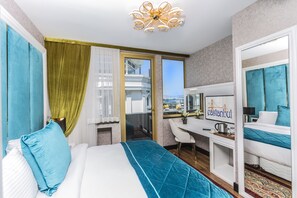 A hotel room with a bed, a desk, a chair, a large mirror, and a view of the city through a window. - Eastanbul Suites (Istanbul)