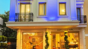 A hotel with a grand entrance, a balcony with black wrought iron railings, and a red carpet leading to the entrance. - Eastanbul Suites (Istanbul)