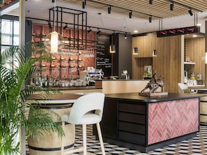 Een moderne bar met een toonbank, barkrukken en een divers aanbod aan flessen en glazen.