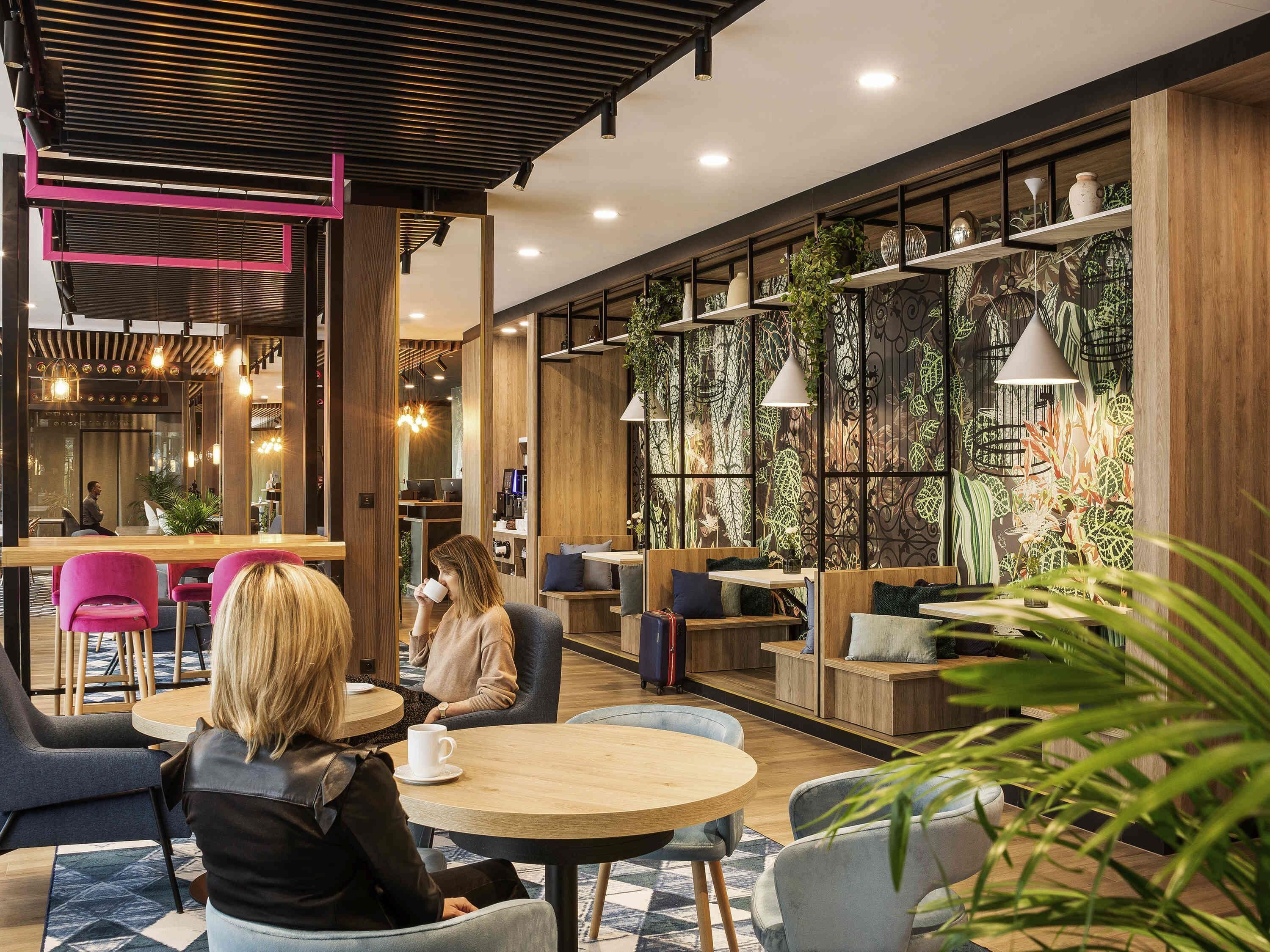 Un espacio interior moderno con mesas redondas, sillas y una combinación de elementos de madera y metal.