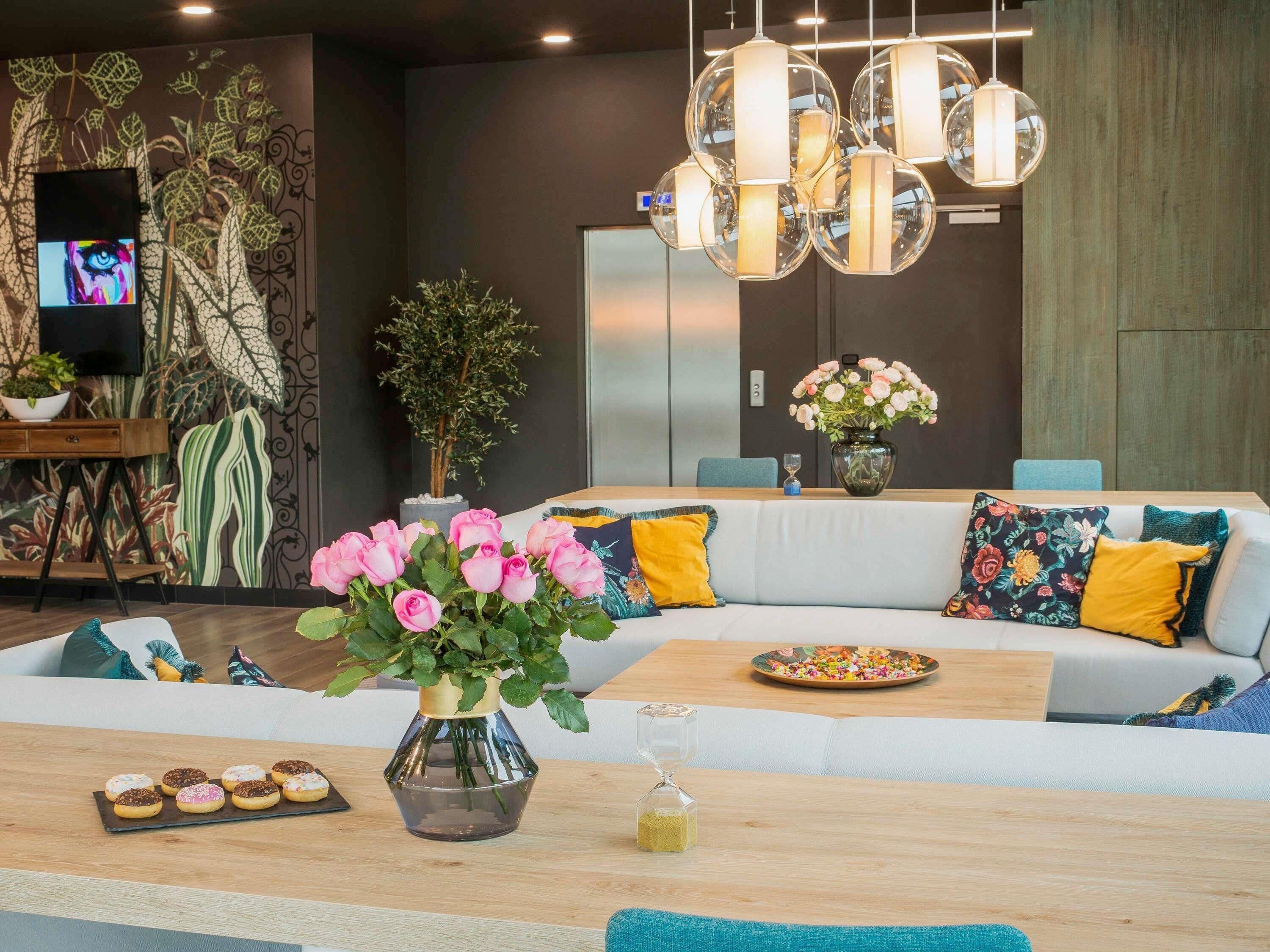A modern living room with a sofa, a coffee table, a vase of flowers, and a television on a stand.