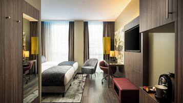 A hotel room with a bed, desk, chair, and a TV.