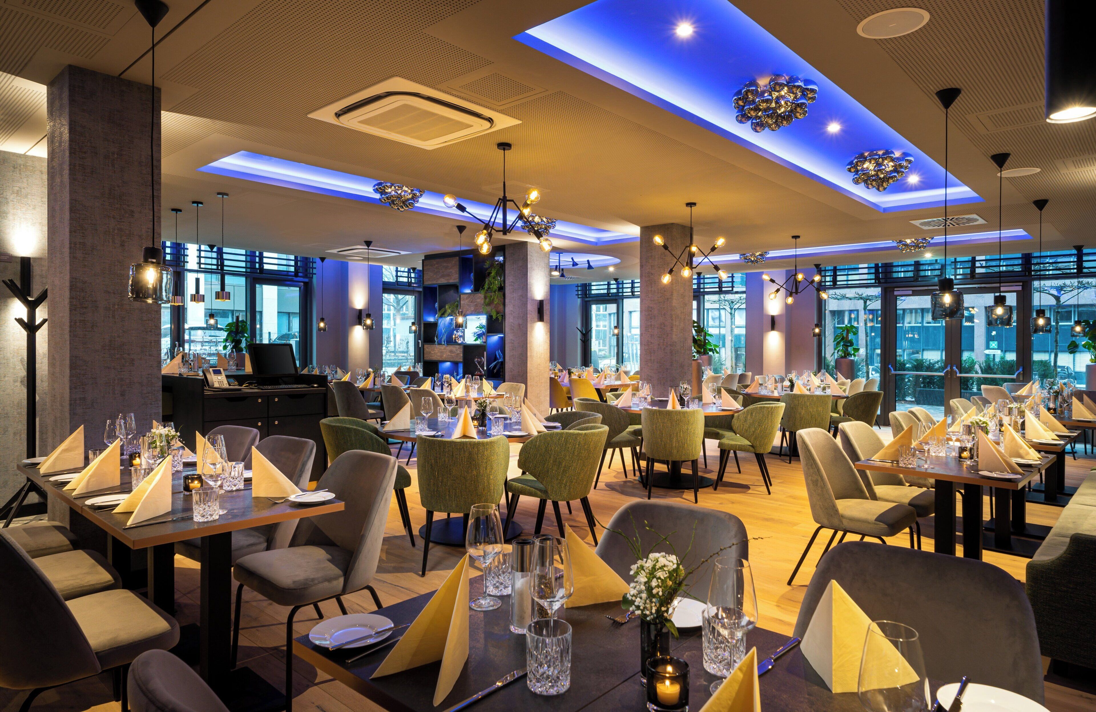 A well-lit restaurant with multiple dining tables, chairs, and a piano in the background.