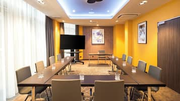 A conference room with a long table, chairs, a flat-screen TV, and artwork on the walls.