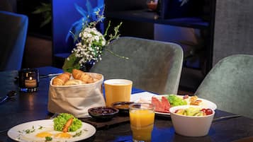 A breakfast setting with croissants, a fruit bowl, and a glass of orange juice on a table.