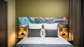 Ein Hotelzimmer mit einem großen Bett, zwei Nachttischen mit Lampen und einem farbenfrohen abstrakten Gemälde an der Wand.