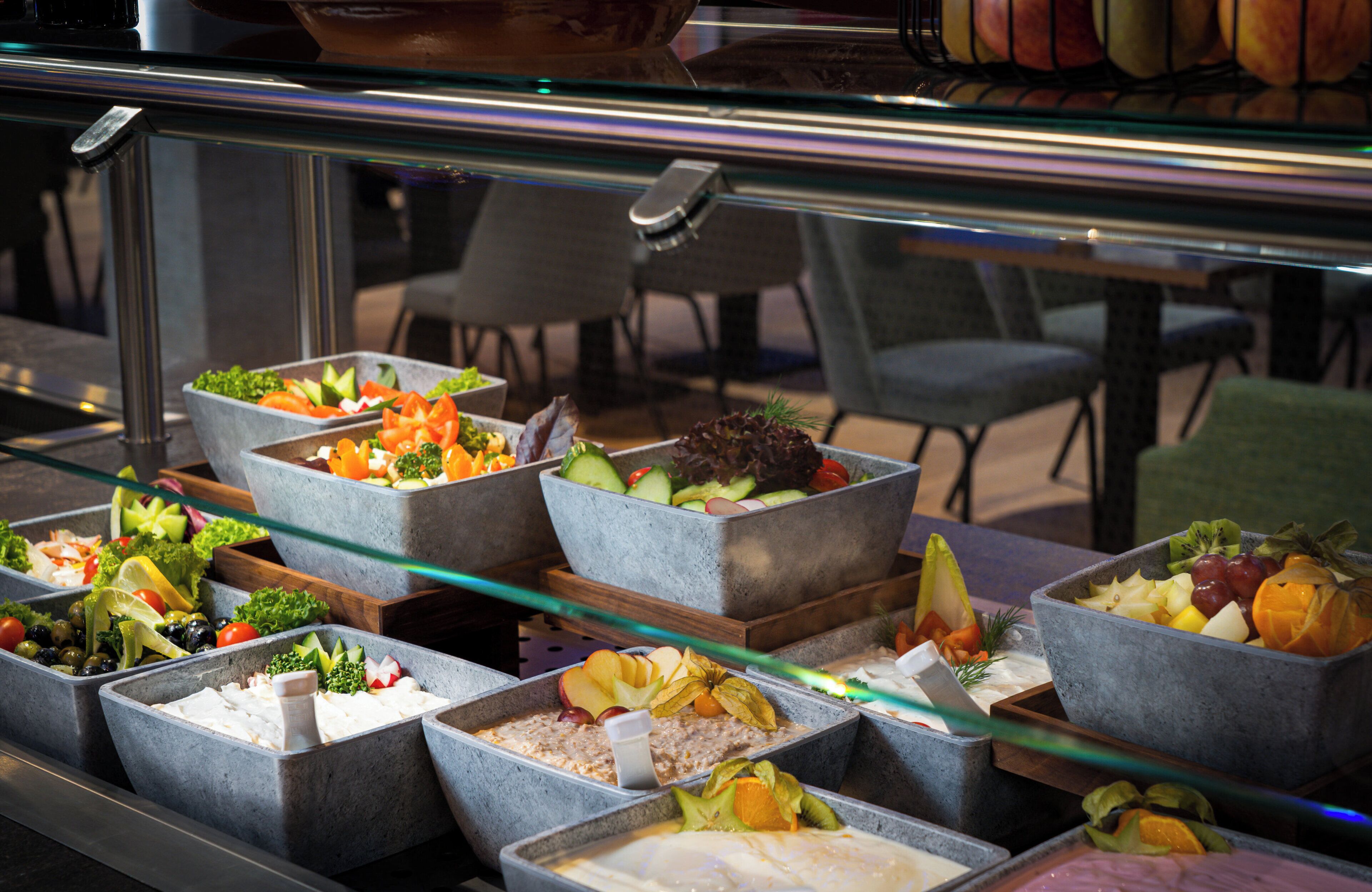 A buffet with various food options including salads, fruits, and cheeses.