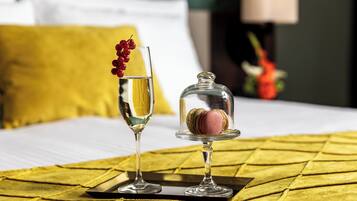 Un lit recouvert d’une couette jaune, une coupe de champagne et un verre d’eau avec des baies rouges, le tout posé sur un plateau.