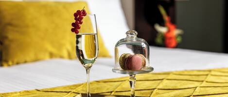 A bed with a yellow quilt, a glass of champagne, and a glass of water with red berries on a tray.