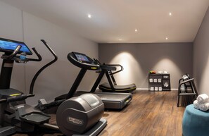 Een moderne sportschool thuis met een loopband, elliptische trainer en krachttrainingapparaat.
