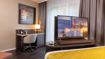 Ein Hotelzimmer mit Bett, Schreibtisch, Stuhl, Fernseher und Couchtisch.