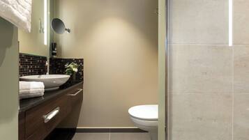 A modern bathroom with a large mirror, a white sink, and a toilet.