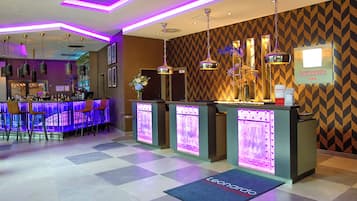 A hotel lobby with a bar area, check-in counters, and a reception desk.