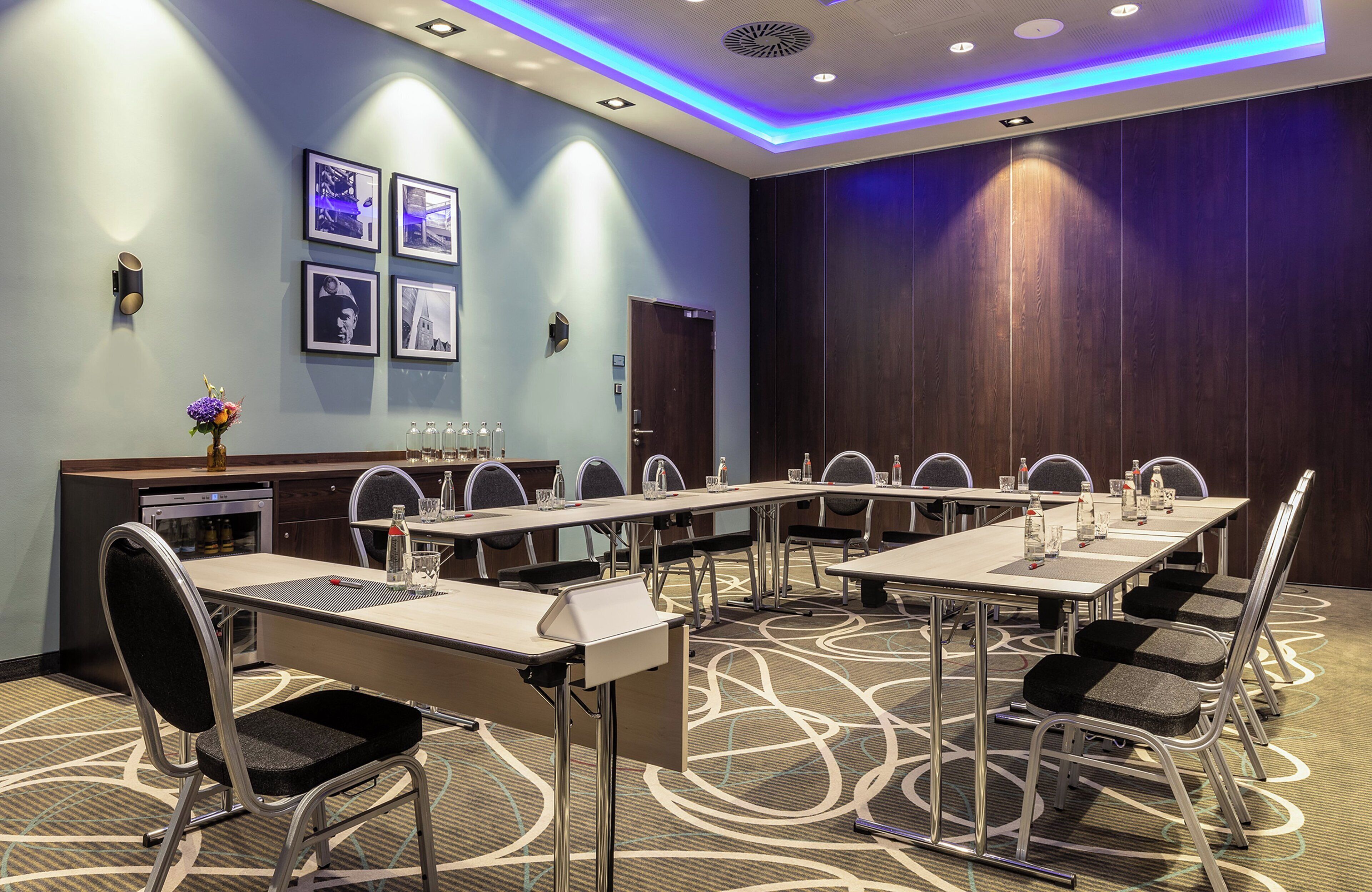 Une salle de conférence avec une longue table, des chaises et un pupitre.