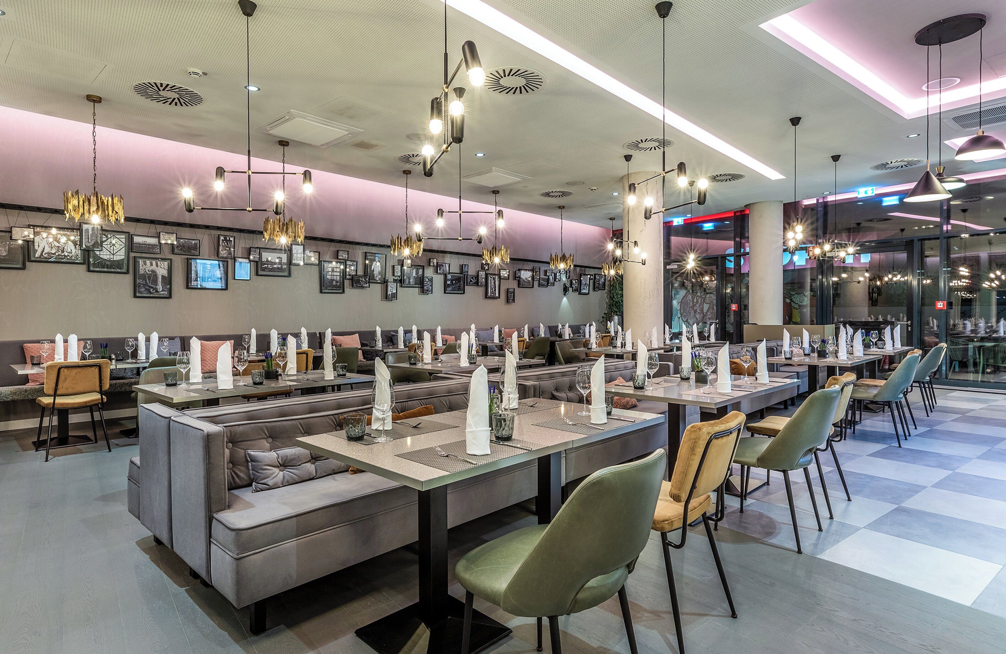 A restaurant with multiple dining areas, each with tables set for two, and a variety of hanging light fixtures.