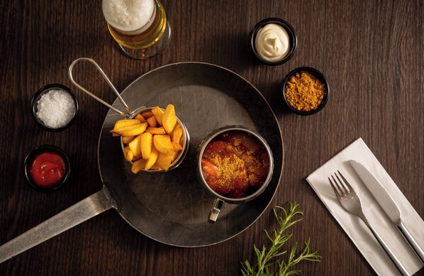 Una mesa de madera con un plato de papas fritas, un recipiente de salsa y aderezos.