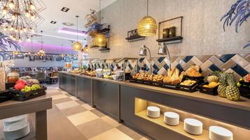 A buffet area with various food items and a seating area in the background.