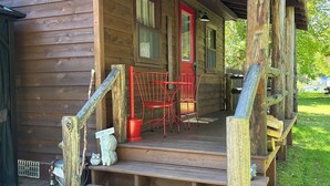 Een houten chalet met veranda, trap en rode deur.