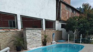 Una piscina con pared de piedra y valla metálica.
