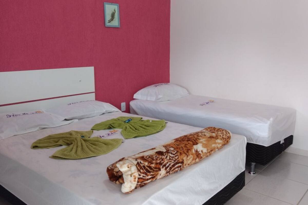 Une chambre d’hôtel avec deux lits, un mur rose et un tableau encadré.