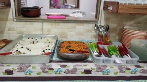Una mesa de buffet con diferentes platos, una ventana con vistas y utensilios de cocina.