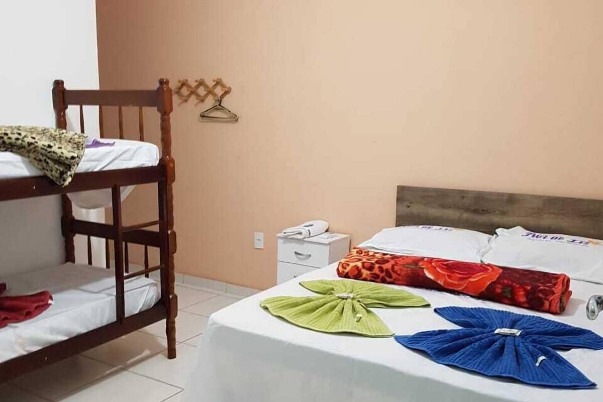 Une chambre avec des lits superposés, une table de chevet et un étendoir fixé au mur.