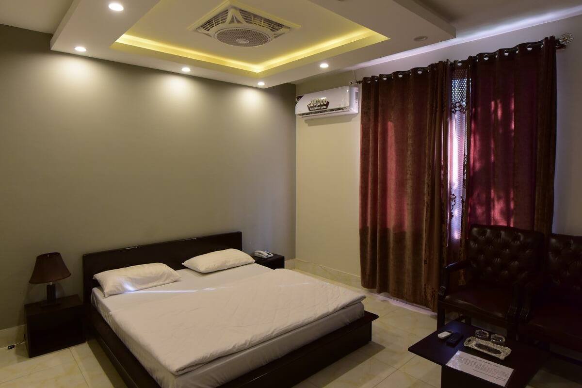 Une chambre moderne avec un grand lit, une table de chevet, une lampe, un climatiseur et un ventilateur de plafond.