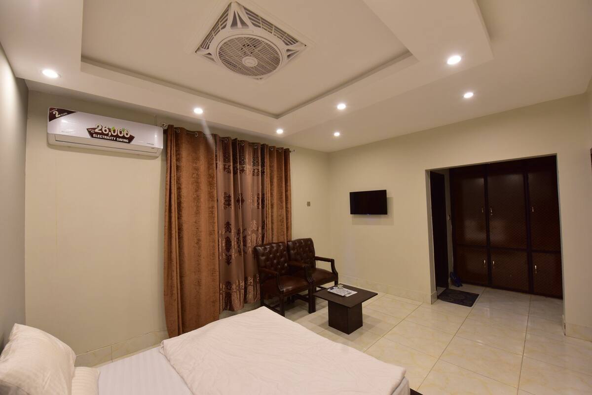 Une chambre d’hôtel avec un lit, un canapé, une petite table, une télévision et une porte.