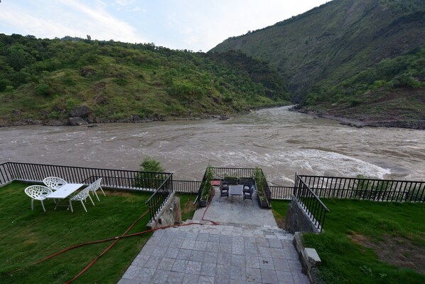 Un patio junto al río con mesas al aire libre y vista fluvial.