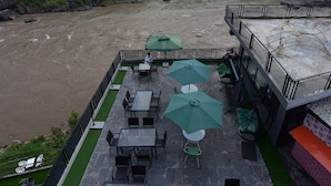A terrace with outdoor seating and a view of a river. - La Orilla Hotel (Muzaffarabad)