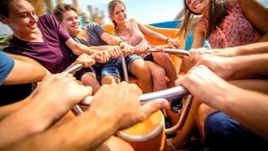 Un grupo de personas en un bote, sujetando el timón.