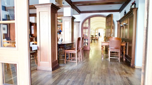 Una habitación amplia con pisos de madera, un comedor con mesa y sillas, y un gran arco que da a otra habitación.