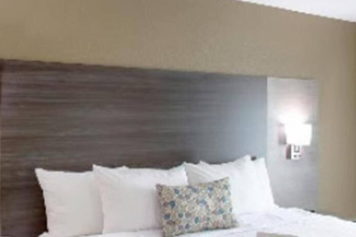 A hotel room with a large bed, a headboard, and a wall-mounted light fixture.