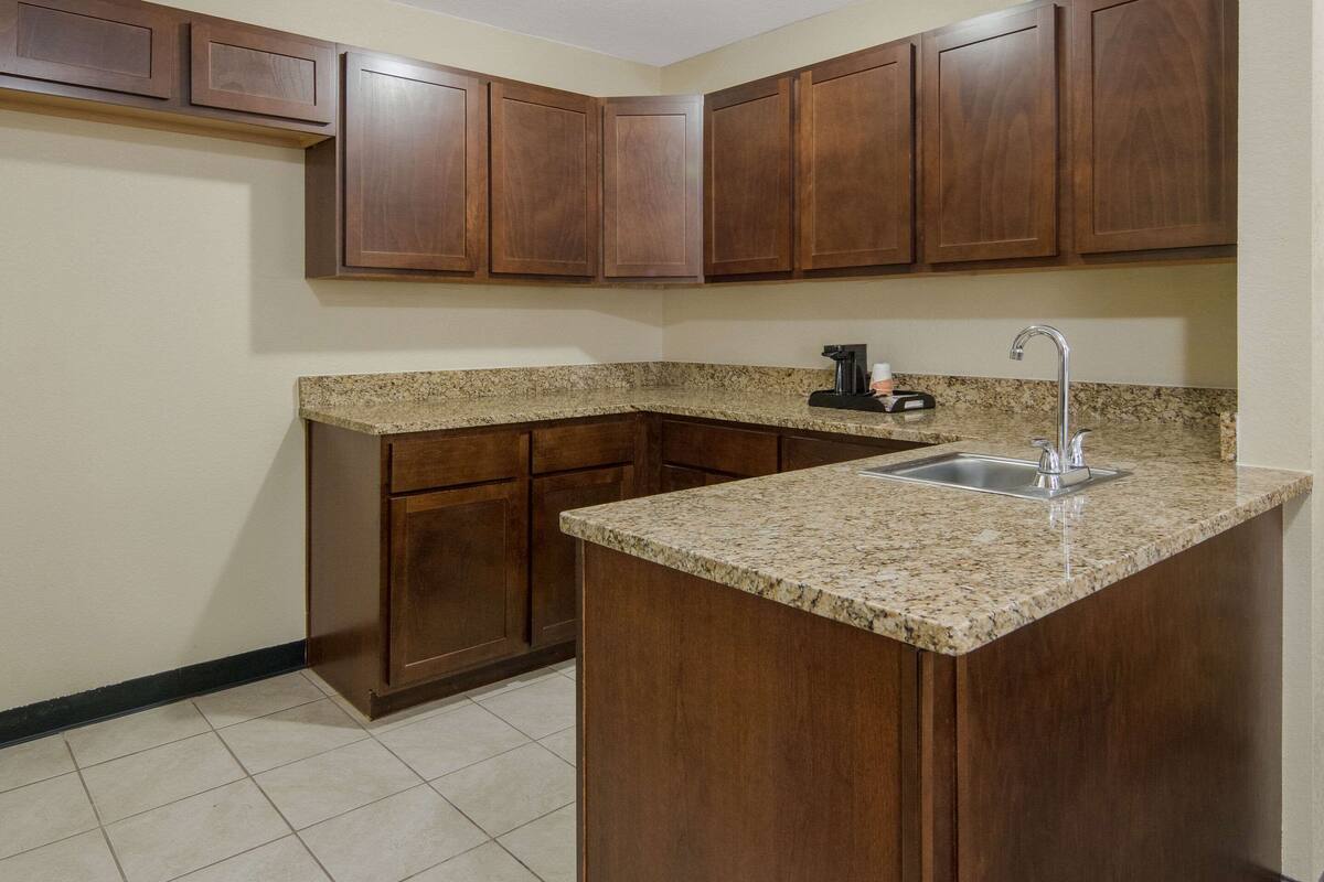 A kitchen with wooden cabinets, granite countertops, and a stainless steel sink.